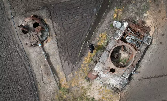 FILE - A peasant plants sunflowers in his garden between a damaged Russian tank and its turret in the village of Velyka Dymerka, Kyiv region, Ukraine, Wednesday, May 17, 2023. (AP Photo/Efrem Lukatsky, File)