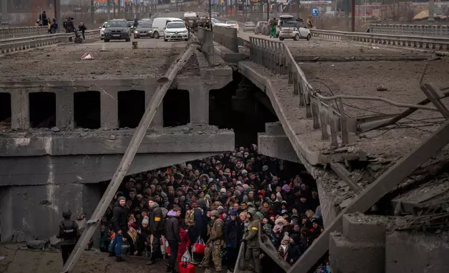 FILE - Ukrainians crowd under a destroyed bridge as they try to flee by crossing the Irpin River on the outskirts of Kyiv, Ukraine, Saturday, March 5, 2022. (AP Photo/Emilio Morenatti, File)