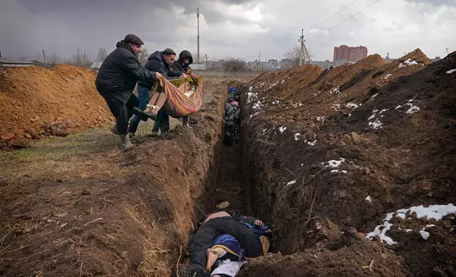FILE - Bodies are placed into a mass grave on the outskirts of Mariupol, Ukraine, Wednesday, March 9, 2022. (AP Photo/Evgeniy Maloletka, File)