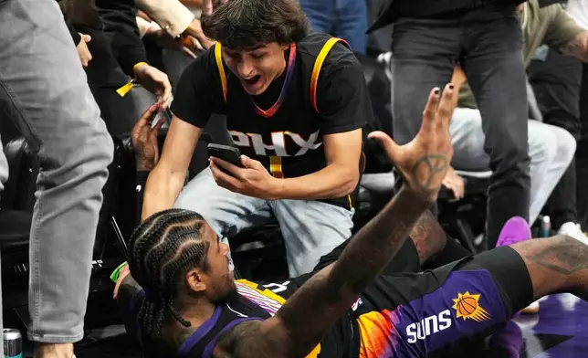 Phoenix Suns guard Jalen Green celebrates with a fan after hitting the game winning basket in double over-time against the Orlando Magic during an NBA basketball game, Saturday, Feb. 21, 2026, in Phoenix. (AP Photo/Rick Scuteri)