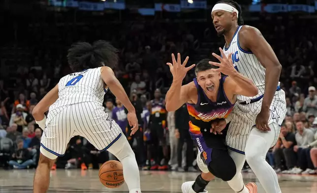 Phoenix Suns guard Grayson Allen reacts after loosing the ball in between Orlando Magic guard Anthony Black (0) and center Wendell Carter Jr. during the second half of an NBA basketball game, Saturday, Feb. 21, 2026, in Phoenix. (AP Photo/Rick Scuteri)