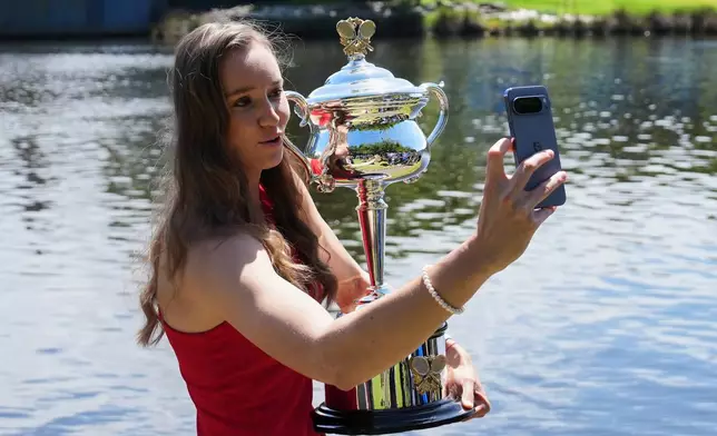 Elena Rybakina of Kazakhstan takes a selfie as she poses with Daphne Akhurst Memorial Cup on the banks of the Yarra River the morning after defeating Aryna Sabalenka of Belarus in the women's singles final at the Australian Open tennis championship in Melbourne, Australia, Sunday, Feb. 1, 2026. (AP Photo/Aaron Favila)