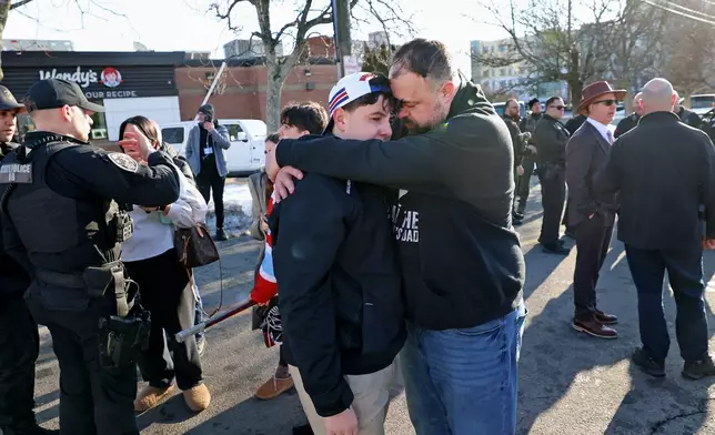 A father hugs his son outside of the Lynch Arena in Pawtucket, R.I., after a shooting at the ice rink, Monday, Feb. 16, 2026. (AP Photo/Mark Stockwell)