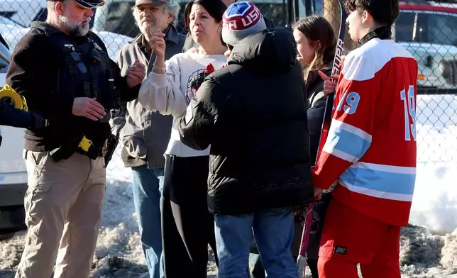 Hockey parents and a player speak to a police officer outside of the Lynch Arena in Pawtucket, R.I., after a shooting at the ice rink, Monday, Feb. 16, 2026. (AP Photo/Mark Stockwell)