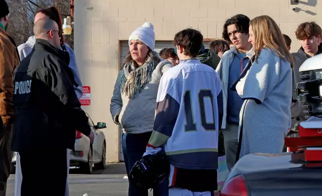 High school hockey players and parents speak to a police officer near the Lynch Arena in Pawtucket, R.I., after a shooting at the ice rink, Monday, Feb. 16, 2026. (AP Photo/Mark Stockwell)