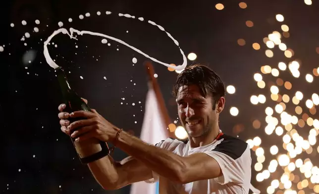 Argentina's Tomas Etcheverry pops champagne to celebrate his victory over Chile's Alejandro Tabilo in the singles final match at the Rio Open tennis tournament in Rio de Janeiro, Sunday, Feb. 22, 2026. (AP Photo/Bruna Prado)