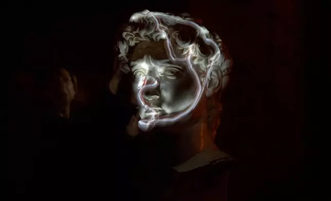 FILE - Stefania Terre, who is blind, uses a small light on her fingers while touching a life-size reproduction of the head of Michelangelo's David as she poses for a long-exposure photograph at the Omero Tactile Museum in Ancona, Italy, Jan. 15, 2026. (AP Photo/Alessandra Tarantino, File)