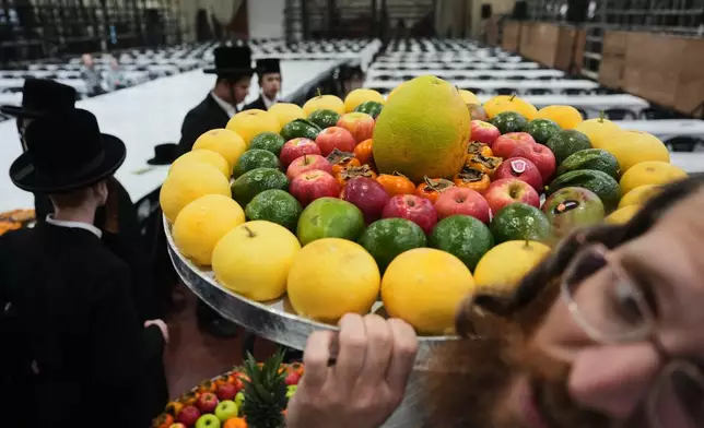 FILE - Ultra-Orthodox Jews from the Sanz Hasidic dynasty prepare a table with fruit to celebrate the Jewish holiday of Tu Bishvat, or the "New Year of the Trees," in Netanya, Israel, Feb. 2, 2026. (AP Photo/Ariel Schalit, File)