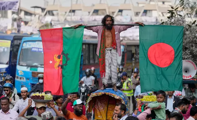 A supporter stands on a rickshaw as he holds a national flag of Bangladesh, right, and a flag of Bangladesh Nationalist Party on a road during an election rally of Tarique Rahman, the son of former Prime Minister Khaleda Zia and chairman of the Bangladesh Nationalist Party (BNP), ahead of national election, on a road in Dhaka, Bangladesh, Sunday, Feb. 8, 2026. (AP Photo/Anupam Nath)