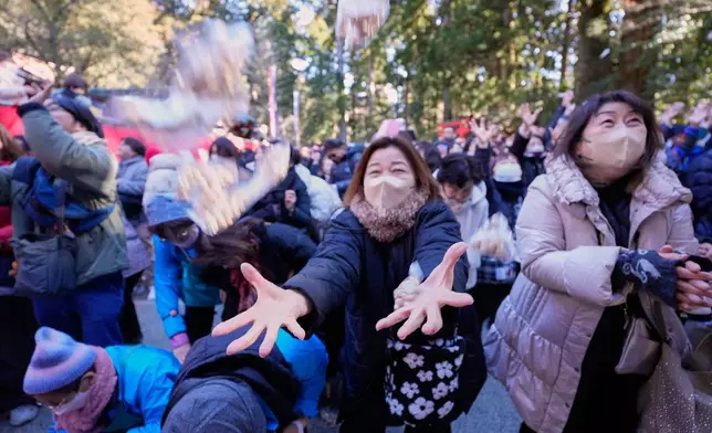 People try to catch lucky beans during the annual Bean Throwing Festival at Hakone Shrine in Hakone, Japan, Tuesday, Feb. 3, 2026. (AP Photo/Eugene Hoshiko)
