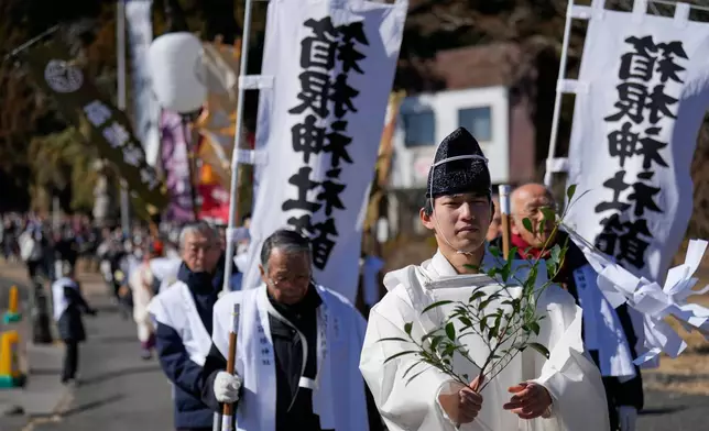 A priest leads participants towards Lake Ashi near Hakone Shrine during the annual Bean Throwing Festival in Hakone, Japan, Tuesday, Feb. 3, 2026. (AP Photo/Eugene Hoshiko)