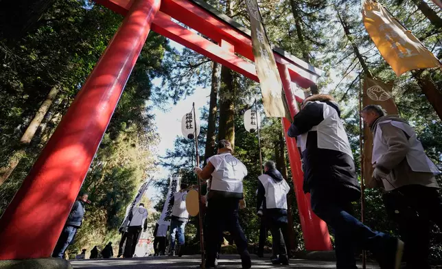 Participants march towards Lake Ashi near Hakone Shrine during the annual Bean Throwing Festival in Hakone, Japan, Tuesday, Feb. 3, 2026. (AP Photo/Eugene Hoshiko)