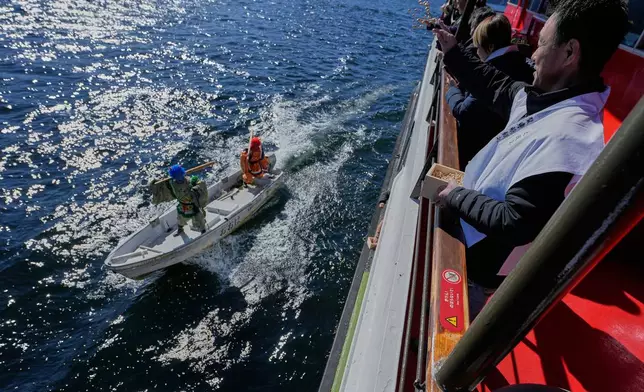 Participants thrown lucky beans to students dressed as 'Oni', or demon-like figures in Japanese folklore, during the annual Bean Throwing Festival, at Lake Ashi in Hakone, Japan, Tuesday, Feb. 3, 2026. (AP Photo/Eugene Hoshiko)
