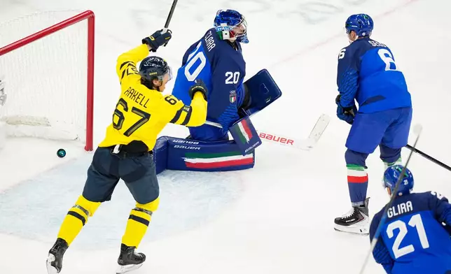 Sweden's Rickard Rakell, left, celebrates a goal scored past Italy's goalkeeper Damian Clara, center, during a preliminary round match of men's ice hockey between Italy and Sweden at the 2026 Winter Olympics, in Milan, Italy, Wednesday, Feb. 11, 2026. (AP Photo/Hassan Ammar)