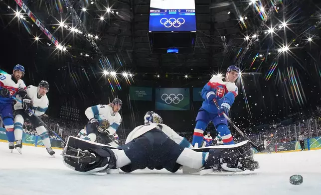 Slovakia's Juraj Slafkovsky (20) scores a goal against Finland's goalkeeper Juuse Saros (74) in the first period during a preliminary round match of men's ice hockey between at the 2026 Winter Olympics, in Milan, Italy, Wednesday, Feb. 11, 2026. (Mike Segar/Pool Photo via AP)