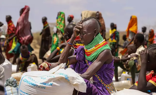 An elderly Turkana woman covers herself from the hot sun after receiving her food ration, in Lomeluku Village, Turkana County, Kenya, Sunday, Feb. 8, 2026. (AP Photo/Patrick Ngugi)