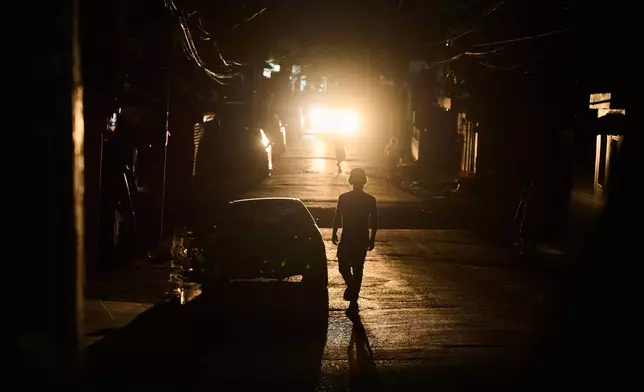 A man walks in a street during a blackout in Santo Domingo, Dominican Republic, Monday, Feb. 23, 2026. (AP Photo/Ricardo Hernandez)