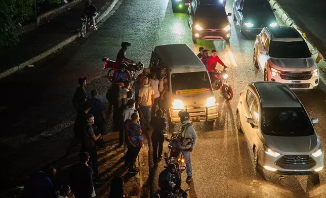 People wait to take transportation during a blackout in Santo Domingo, Dominican Republic, Monday, Feb. 23, 2026. (AP Photo/Ricardo Hernandez)