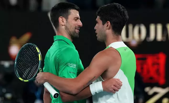 Carlos Alcaraz, right, of Spain is congratulated by Novak Djokovic, left, of Serbia after winning the men's singles final at the Australian Open tennis championship in Melbourne, Australia, Sunday, Feb. 1, 2026. (AP Photo/Dita Alangkara)