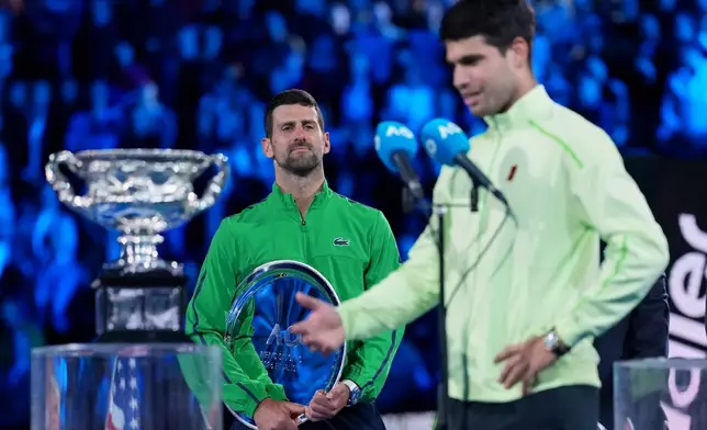 Novak Djokovic of Serbia watches Carlos Alcaraz of Spain give his victory speech after winning the men's singles final at the Australian Open tennis championship in Melbourne, Australia, Sunday, Feb. 1, 2026. (AP Photo/Aaron Favila)