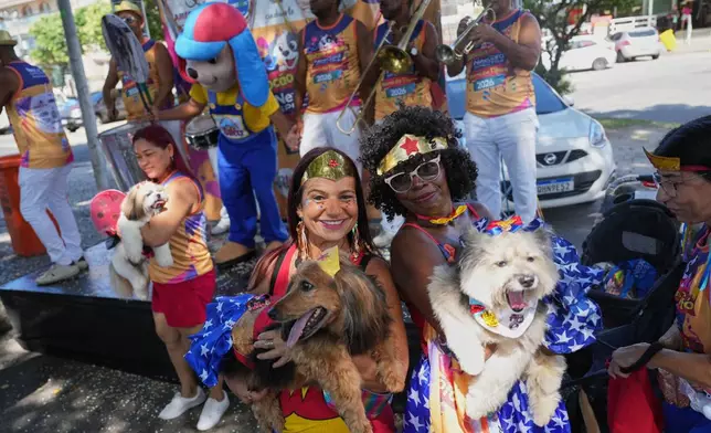 Owners and their pets pose for a photo at the "Blocao" Carnival dog parade in Rio de Janeiro, Saturday, Feb. 14, 2026. (AP Photo/Silvia Izquierdo)