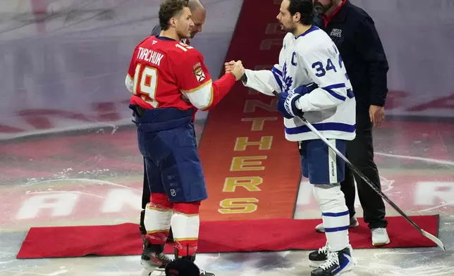 Florida Panthers left wing Matthew Tkachuk (19) and Toronto Maple Leafs center Auston Matthews (34) shake hands before an NHL hockey game honoring the players on the USA team winning the gold medal at the Milan Cortina Olympics, Thursday, Feb. 26, 2026, in Sunrise, Fla. (AP Photo/Lynne Sladky)