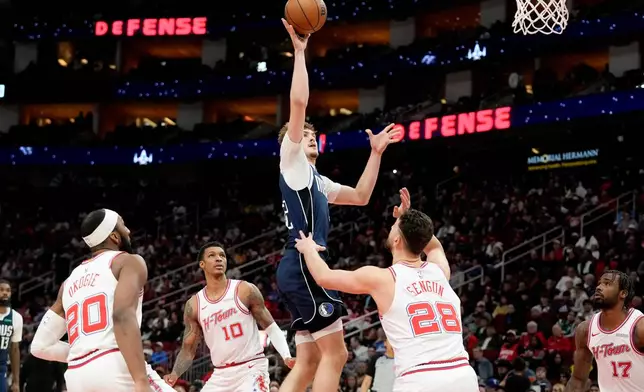 Dallas Mavericks forward Cooper Flagg, center, shoots as Houston Rockets center Alperen Sengun (28) defends during the first half of an NBA basketball game Saturday, Jan. 31, 2026, in Houston. (AP Photo/Eric Christian Smith)
