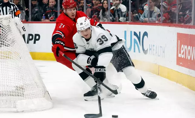 Los Angeles Kings' Jeff Malott (39) protects the puck from Carolina Hurricanes' Alexander Nikishin (21) during the first period of an NHL hockey game in Raleigh, N.C., Sunday, Feb. 1, 2026. (AP Photo/Karl DeBlaker)
