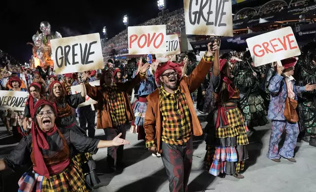 Performers of Academicos de Niteroi samba school, hold signs that read "Strike" and "People" during Carnival celebrations at the Sambadrome in Rio de Janeiro, Sunday, Feb. 15, 2026. (AP Photo/Silvia Izquierdo)