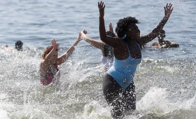 Revelers cool off in the waters of Flamengo beach during the Amigos da Onca Carnival street party, in Rio de Janeiro, Saturday, Feb. 14, 2026. (AP Photo/Bruna Prado)