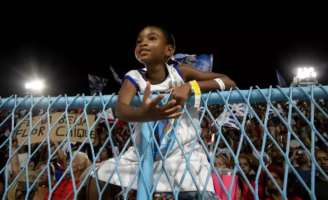 A child watches a parade of the Beija-Flor samba school during Carnival celebrations at the Sambadrome in Rio de Janeiro, Monday, Feb. 16, 2026. (AP Photo/Bruna Prado)