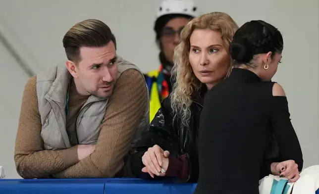 Individual Neutral Athlete Adeliia Petrosian, right, speaks with coach Eteri Tutberidze, center, and choreographer Daniil Gleikhengauz, during a figure skating practice session at the 2026 Winter Olympics, in Milan, Italy, Monday, Feb. 16, 2026. (AP Photo/Stephanie Scarbrough)