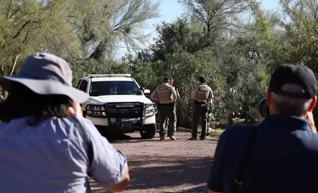 Photographers take images of sheriff's deputies outside the home of Nancy Guthrie in Tucson, Ariz., Sunday, Feb. 22, 2026. (AP Photo/Felicia Fonseca)