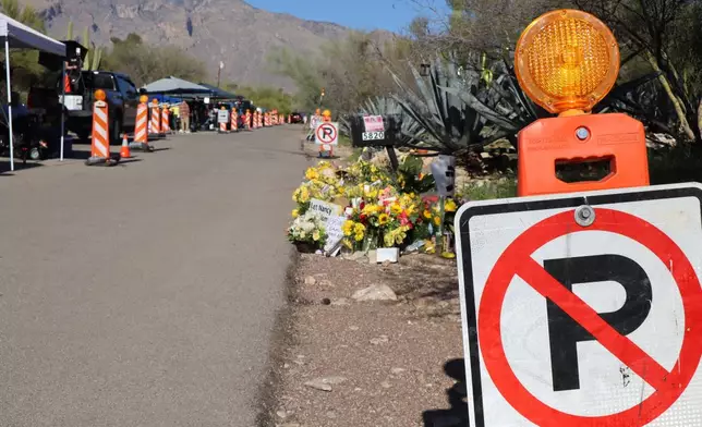 "No parking" signs stand along one side of the road that Nancy Guthrie lives on in Tucson, Ariz., Sunday, Feb. 22, 2026, while canopies and vehicles of people covering the investigation line the other side. (AP Photo/Felicia Fonseca)