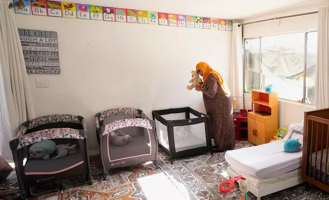 Samsam Khalif shows a child a stuffed animal as she prepares for nap time at her home-based child care center Friday, Jan. 30, 2026, in San Diego. (AP Photo/Gregory Bull)