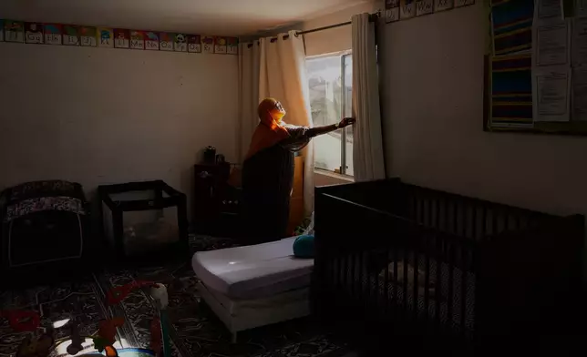 Samsam Khalif closes curtains as she prepares for nap time at her home-based child care center Friday, Jan. 30, 2026, in San Diego. (AP Photo/Gregory Bull)