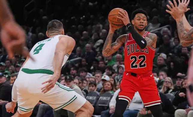 Chicago Bulls guard Anfernee Simons (22) looks to pass while pressured by Boston Celtics center Nikola Vucevic (4) during the first half of an NBA basketball game, Wednesday, Feb. 11, 2026, in Boston. (AP Photo/Charles Krupa)