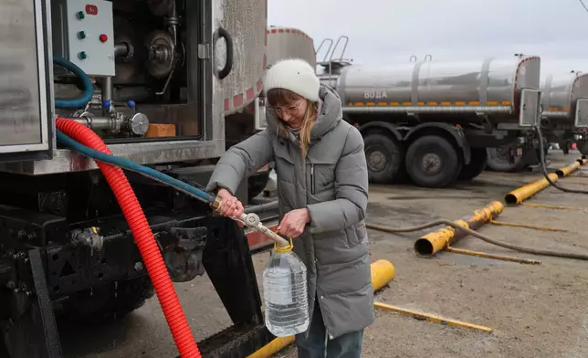 A woman gets drinking water distributed by authorities in the city of Donetsk in the Russian-controlled part of eastern Ukraine, on Thursday, Feb. 19, 2026. (AP Photo)