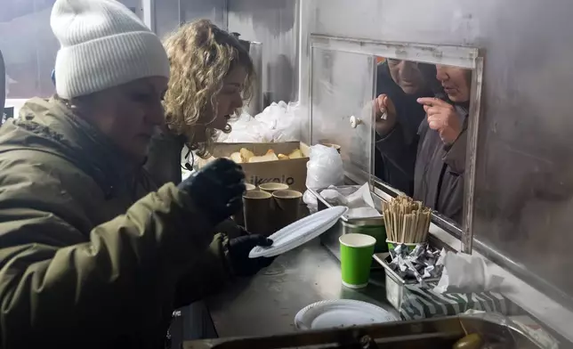 Veterans of the 3rd Separate Assault Brigade of Ukraine's Armed Forces serve free hot meals in a residential neighborhood for people without power in their homes in Kyiv, Ukraine, Saturday, Jan. 31, 2026.(AP Photo/Vladyslav Musiienko)