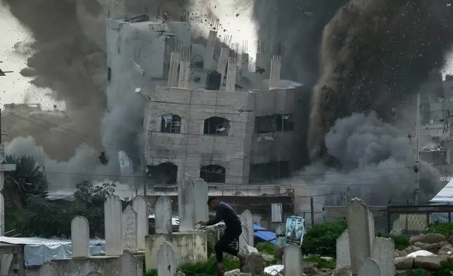 A man runs for cover in a graveyard as smoke rises from an Israeli military strike on a building in the Zeitoun neighborhood of Gaza City, Friday, Feb. 6, 2026. (AP Photo/Jehad Alshrafi)