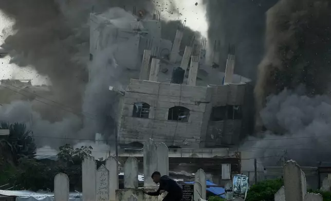 A man runs for cover through a graveyard as smoke rises from an Israeli military strike on a building in the Zeitoun neighborhood of Gaza City, Friday, Feb. 6, 2026. (AP Photo/Jehad Alshrafi)
