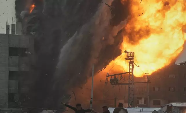 Three men take cover in a graveyard as smoke and flames rise from an Israeli military strike on a building in the Zeitoun neighborhood of Gaza City, Friday, Feb. 6, 2026. (AP Photo/Jehad Alshrafi)