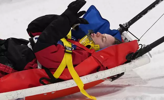 Canada's Cassie Sharpe blows kisses as medics stretcher her off after crashing during the women's freestyle skiing halfpipe qualifications at the 2026 Winter Olympics, in Livigno, Italy, Thursday, Feb. 19, 2026. (AP Photo/Gregory Bull)