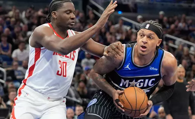 Orlando Magic forward Paolo Banchero, right, looks for a shot against Houston Rockets center Clint Capela (30) during the first half of an NBA basketball game, Thursday, Feb. 26, 2026, in Orlando, Fla. (AP Photo/John Raoux)