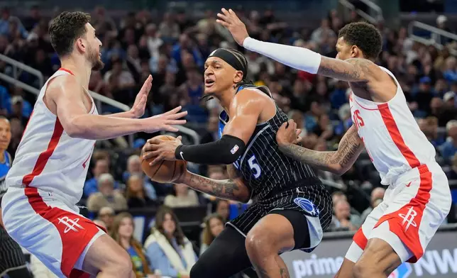 Orlando Magic forward Paolo Banchero (5) makes a move to the basket agate goes between Houston Rockets center Alperen Sengun, left, and forward Jabari Smith Jr., right, during the first half of an NBA basketball game, Thursday, Feb. 26, 2026, in Orlando, Fla. (AP Photo/John Raoux)