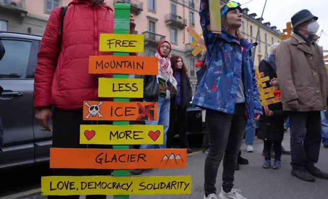 A demonstrator holding a cardboard cutouts representing trees cut down for a new bobsled run takes part in a march against the environmental impact of the Milan Cortina Winter Olympics and the presence of U.S. Immigration and Customs Enforcement agents, in Milan, Saturday Feb. 7, 2026. (Claudio Furlan/LaPresse via AP)