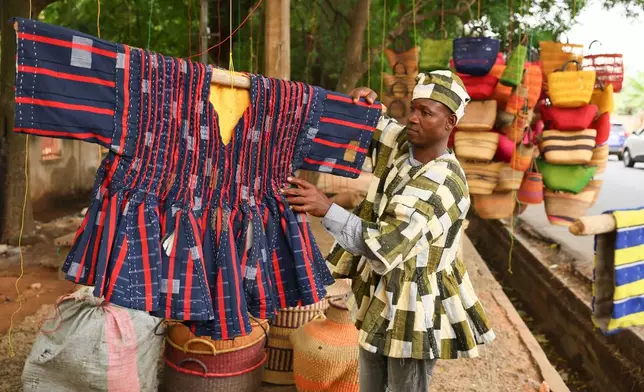 Clement Azaabire hangs traditional fugu garments under a tree on display for sale along a street in Accra, Ghana, Wednesday, Feb. 18, 2026. (AP Photo/Tsraha Yaw)