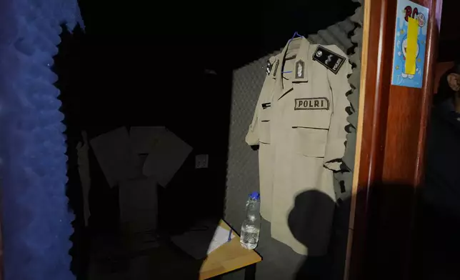 A fake Indonesian police shirt hangs inside a scam center in O'Smach, Cambodia, Monday, Feb. 2, 2026. (AP Photo/Sakchai Lalit)