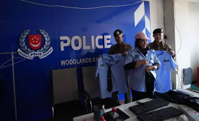 A Thai journalist wears a fake Singapore police uniform at a mock-up set resembling a police station inside a scam compound in O'Smach, Cambodia, Monday, Feb. 2, 2026. (AP Photo/Sakchai Lalit)