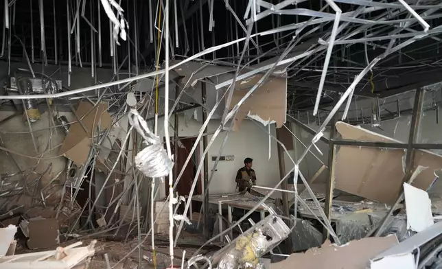 A journalist walks inside a damaged work station at a scam compound in O'Smach, Cambodia, Monday, Feb. 2, 2026, (AP Photo/Sakchai Lalit)